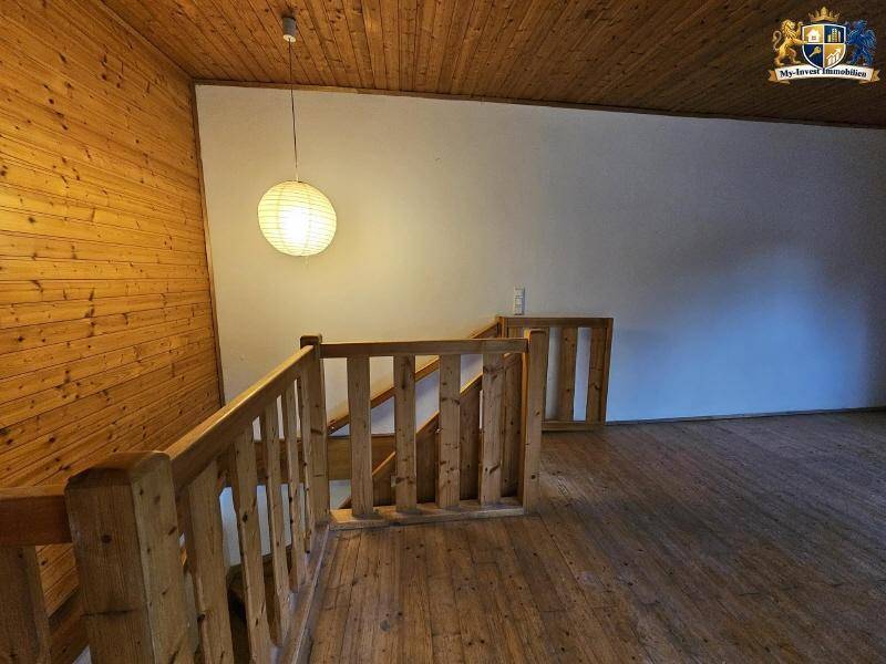 Treppenhaus mit Holzgeländer und Holzverkleidung an Decke und Wänden.