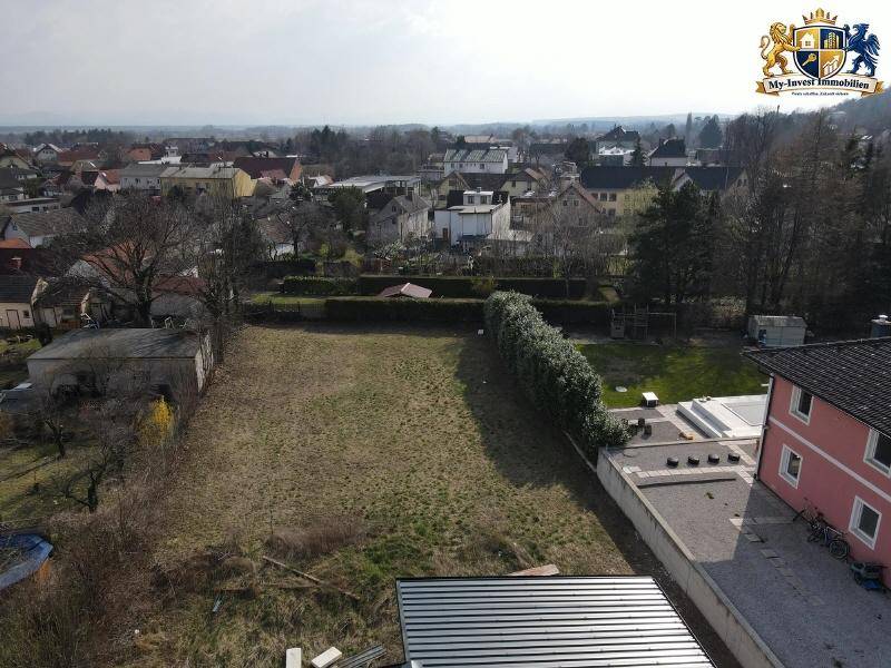 Übersichtliche Luftaufnahme eines unbebauten Grundstücks mit angrenzenden Häusern und weitem Blick.
