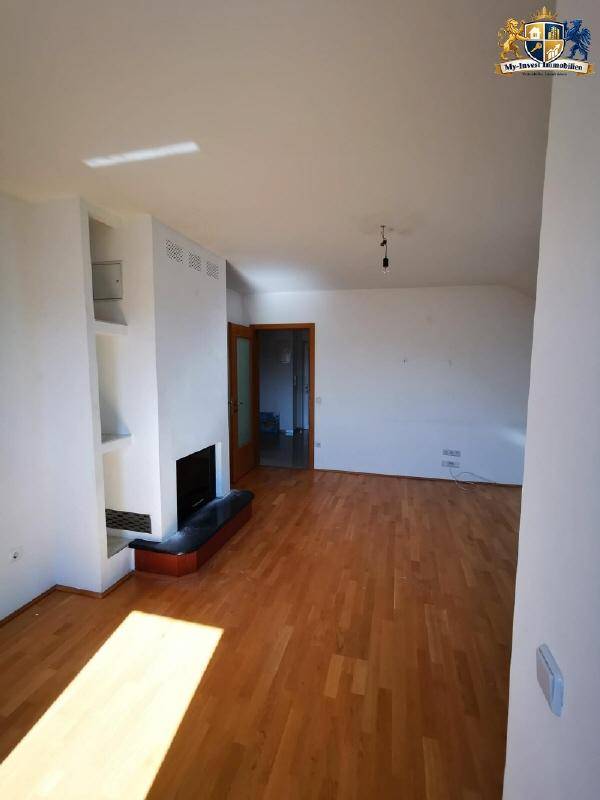 Geräumiges Wohnzimmer mit hellem Parkettboden und einem modernen Kamin, bereit zur individuellen Gestaltung.
