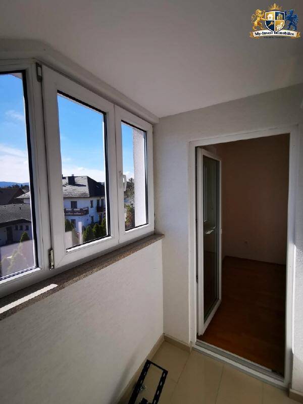 Heller Balkon mit weiten Ausblicken über die umliegende Wohngegend und die hügelige Landschaft.