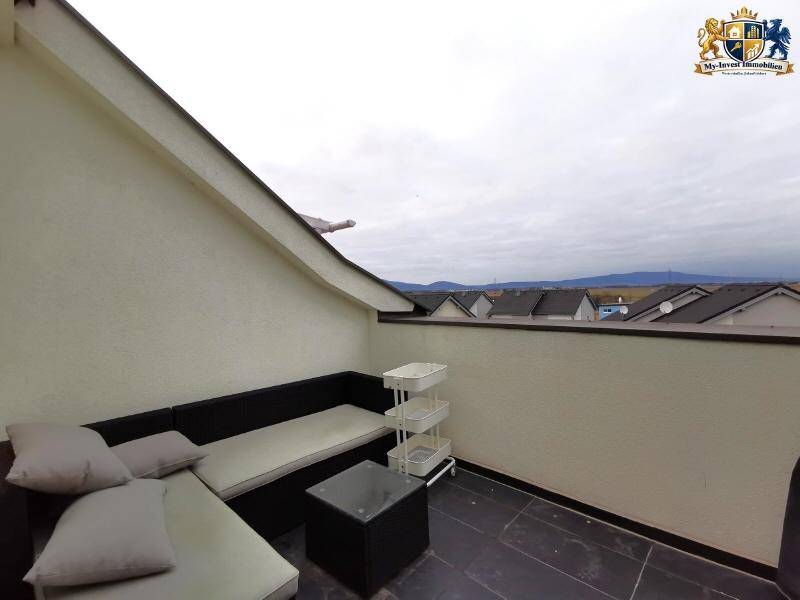 Möblierte Dachterrasse mit Sitzgelegenheiten und weitem Blick über Dächer und Landschaft.