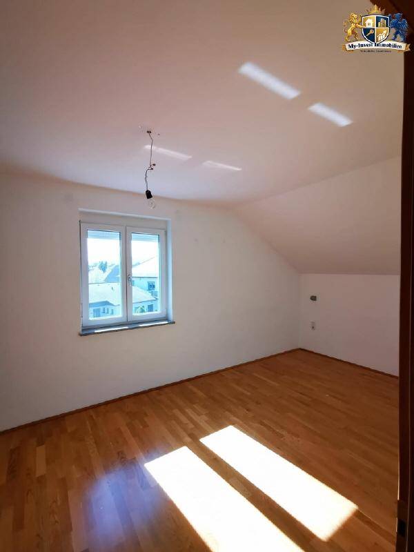 Lichtdurchflutetes Schlafzimmer mit Parkettboden, Dachschräge und großzügigem Tageslichteinfall.