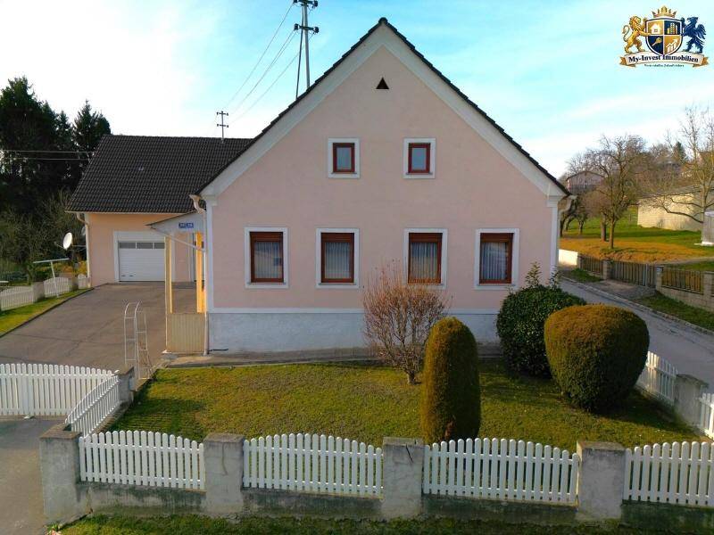 Vorderansicht des Einfamilienhauses mit gepflegtem Vorgarten und weißem Lattenzaun.