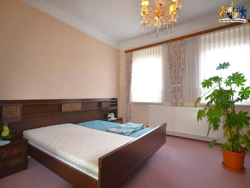 Gemütliches Schlafzimmer mit Doppelbett, Teppichboden und großen Fenstern, die viel Licht hereinlassen.