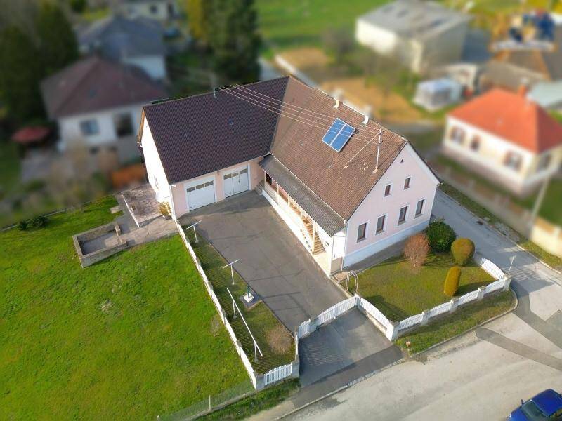 Luftaufnahme des Einfamilienhauses mit Doppelgarage, Auffahrt und großem Grundstück.