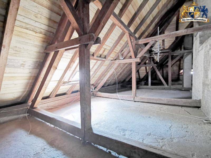 Unausgebauter Dachbodenbereich mit freiliegenden Holzbalken und Dachschrägen, bereit für die Gestaltung.