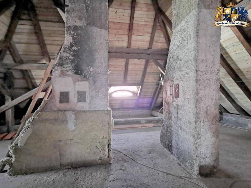 Dachboden mit zwei großen Betonpfeilern und sichtbarer Holzkonstruktion, bietet Ausbaupotenzial.