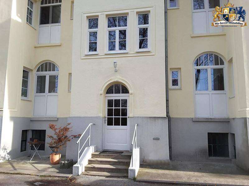 Klassische Gebäudefassade mit weißer Eingangstür und symmetrischen Fenstern, im Altbaustil.