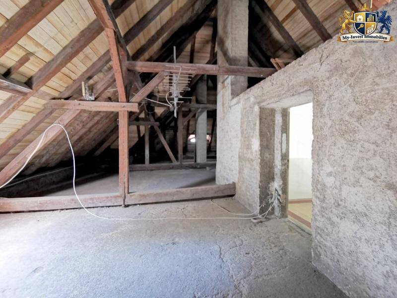 Großer Dachboden mit sichtbarer Holzkonstruktion und unfertigen Wänden.