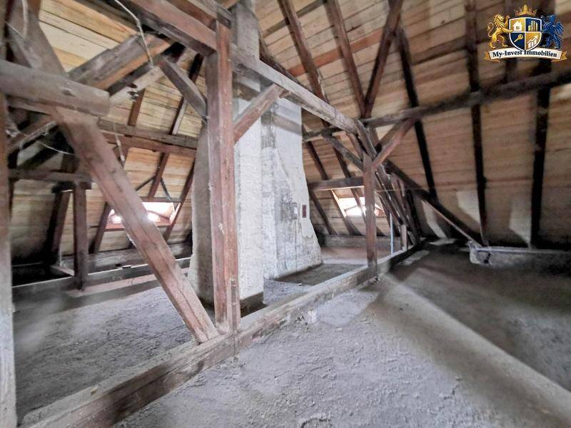 Dachboden mit massiven Stützpfeilern und natürlichem Lichteinfall durch Dachfenster.