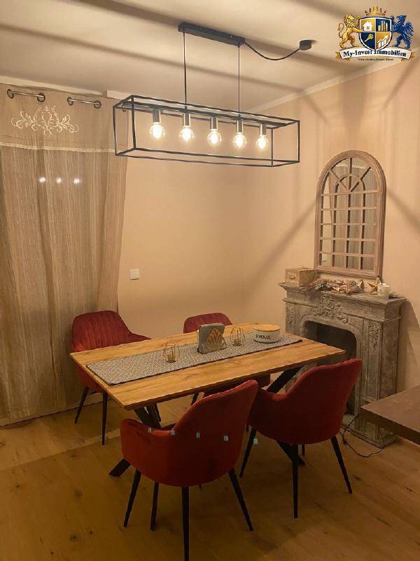 Gemütlicher Essbereich mit Holztisch, roten Stühlen und einem dekorativen Wandspiegel.