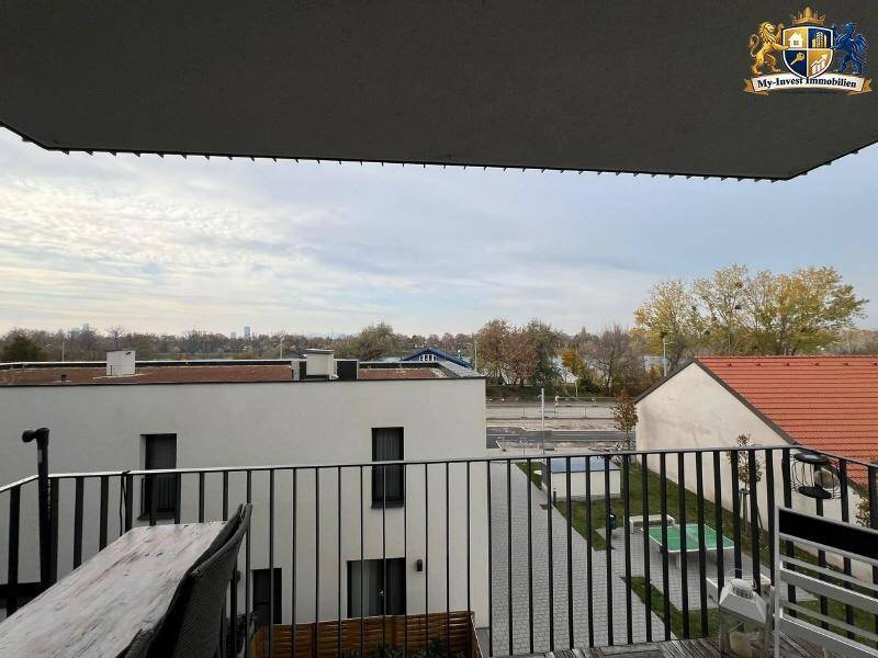 Balkon mit weitem Blick über die Dächer und die grüne Umgebung, unter einem bewölkten Himmel.