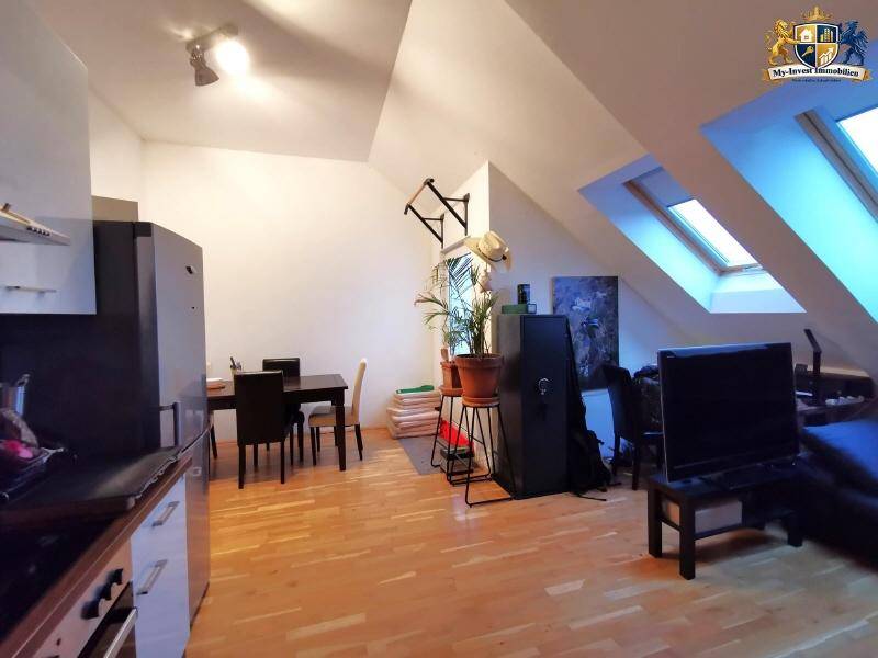 Heller Wohn- und Essbereich in einer Dachgeschosswohnung mit Holzboden und Dachfenstern.
