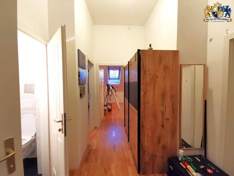 Heller Flur mit Holzfußboden, einem Kleiderschrank und Zugang zu weiteren Räumen.