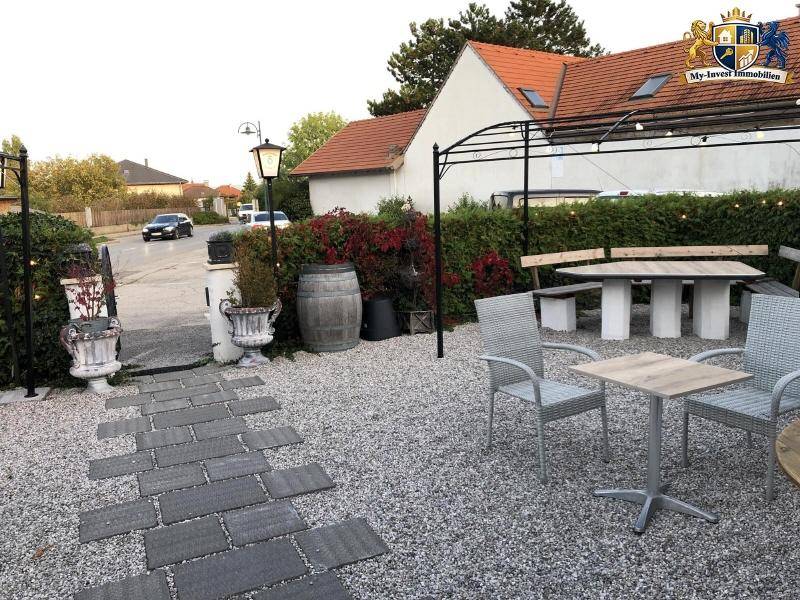 Außenbereich mit Kiesboden, verschiedenen Sitzgelegenheiten und einem gepflasterten Weg zum Gebäude.