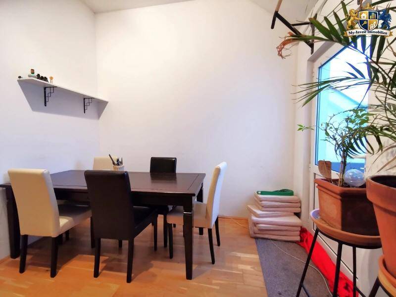 Essbereich mit dunklem Holztisch und Stühlen, beleuchtet durch ein großes Fenster.