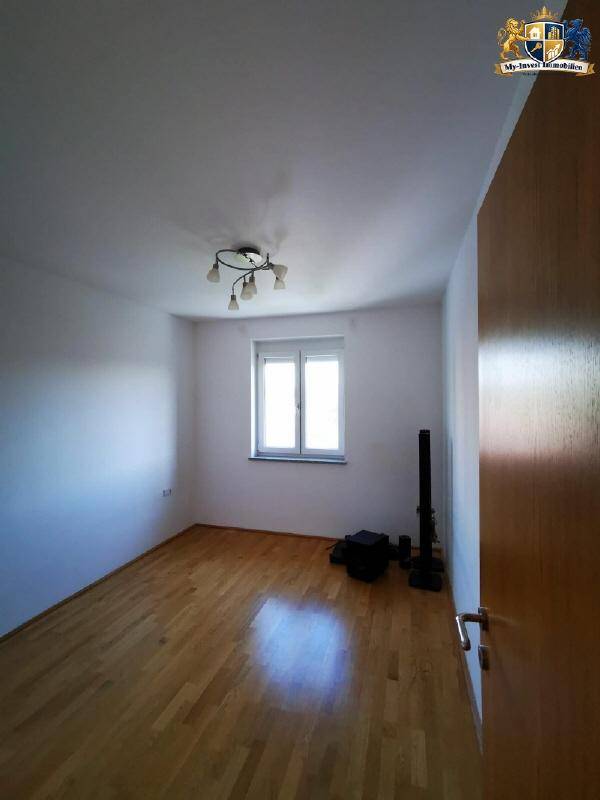 Gemütliches Schlafzimmer mit Holzparkettboden, weiß gestrichenen Wänden und einem Fenster.