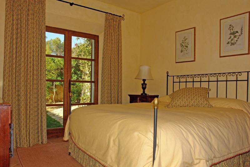 Gemütliches Schlafzimmer mit Doppelbett, traditionellen Möbeln und Zugang zum Garten.