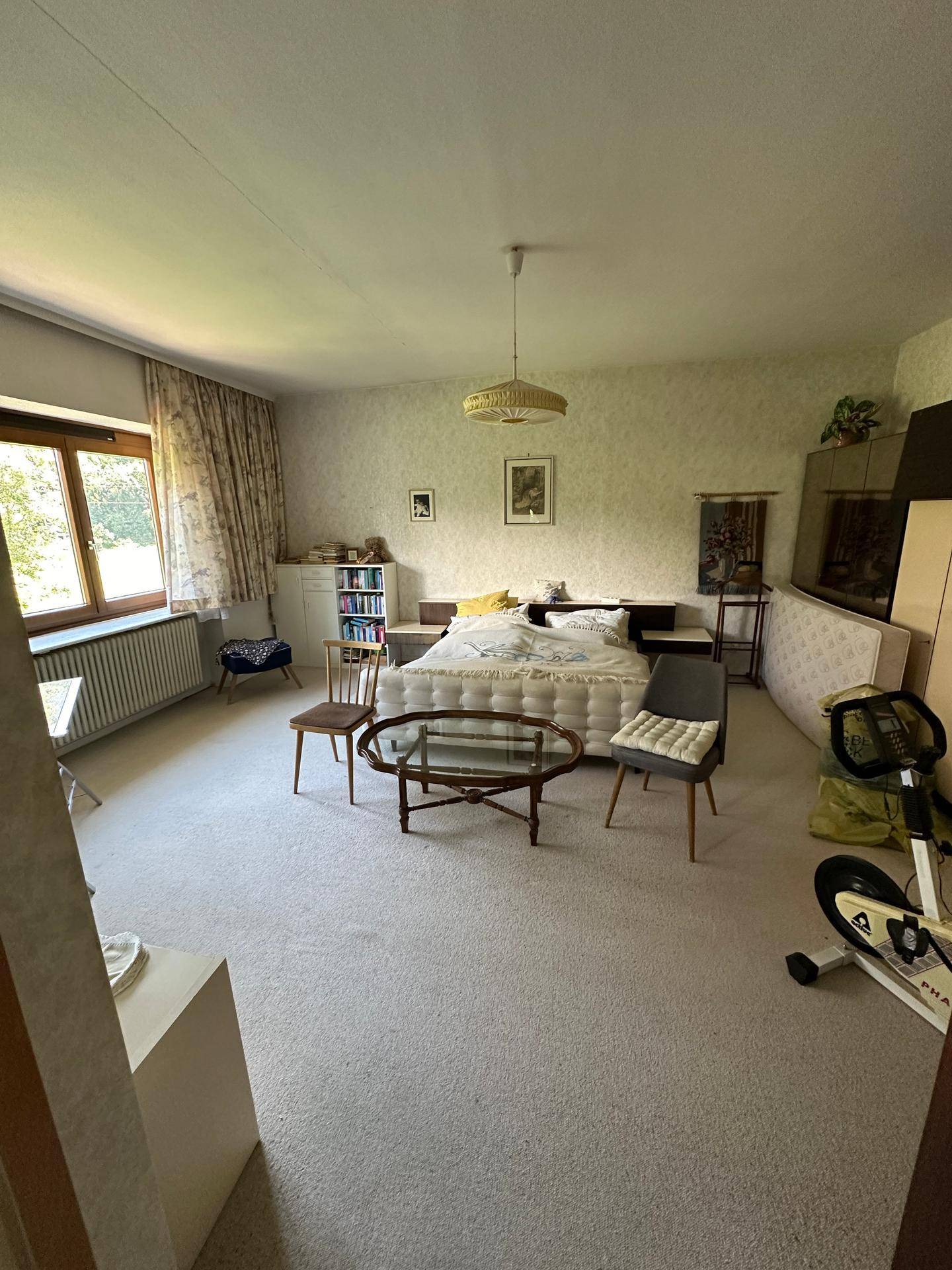 Geräumiges Schlafzimmer mit Teppichboden, großem Fenster und traditioneller Möblierung.