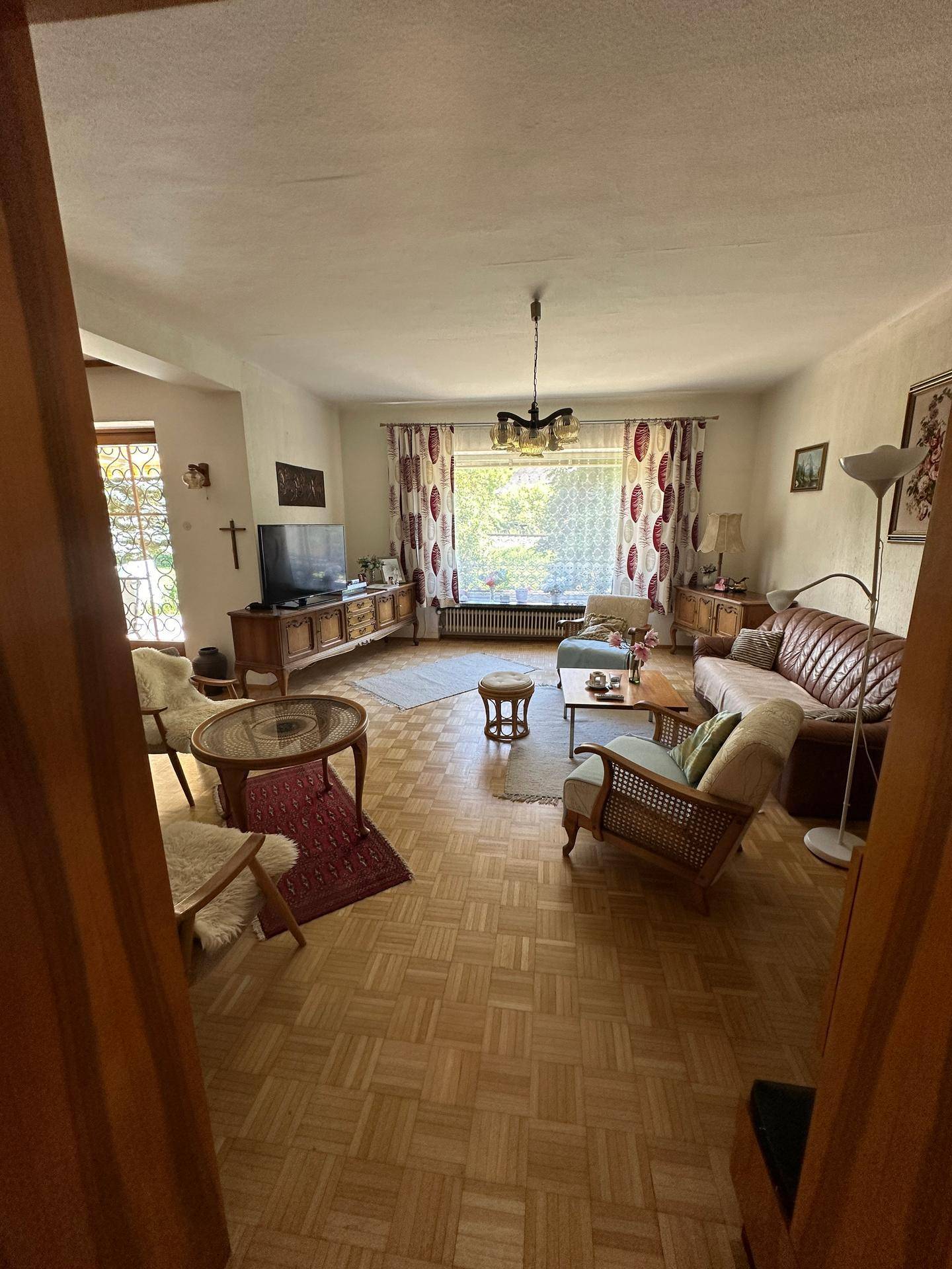 Gemütliches Wohnzimmer mit Parkettboden, traditionellen Möbeln und Blick ins Grüne.
