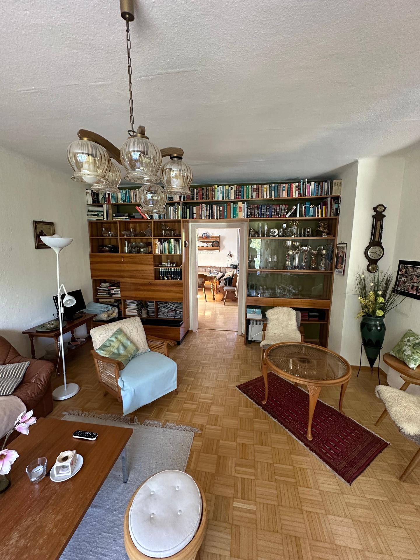 Wohnzimmer mit Parkettboden, Bücherregalen und traditioneller Einrichtung, die Gemütlichkeit ausstrahlt.