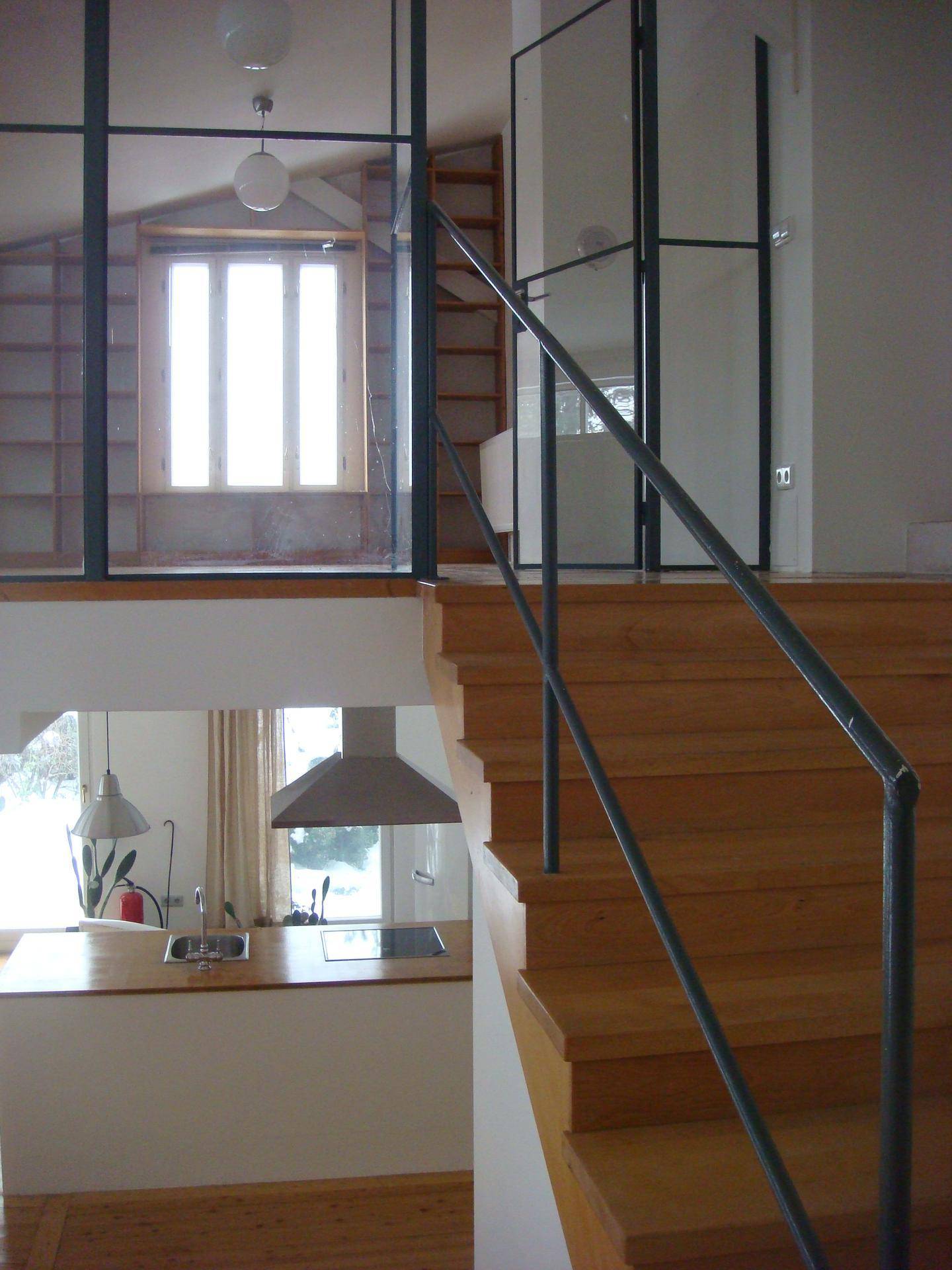 Offene Treppe mit Metallgeländer führt zu einer Galerie, darunter ist ein Teil der Küche sichtbar.