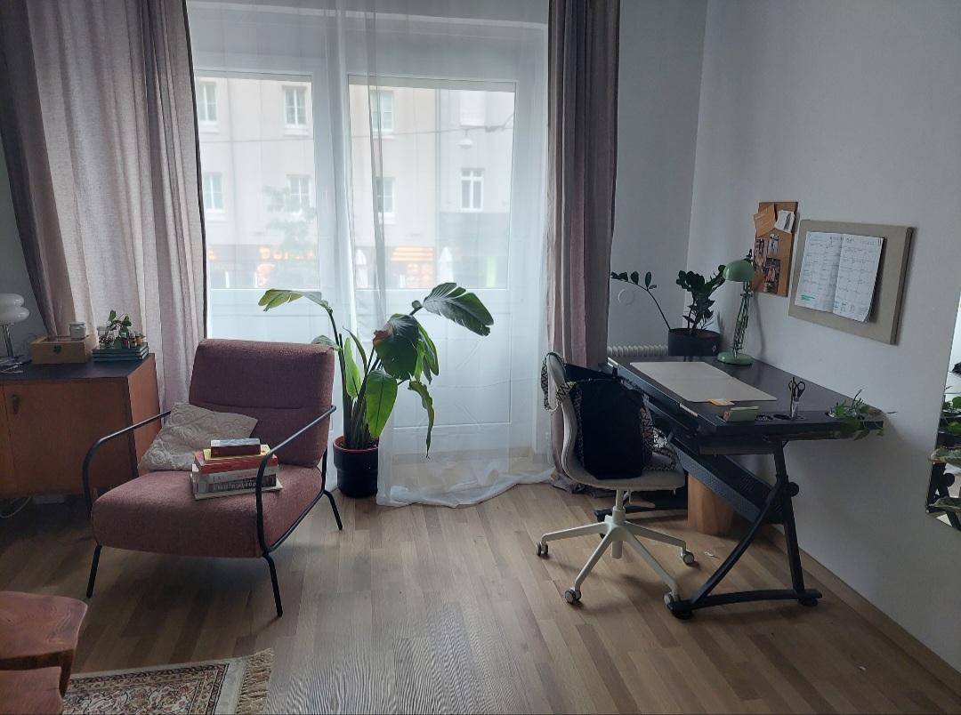Heller Raum mit Schreibtisch, Sessel und großem Fenster, das viel Tageslicht hereinlässt.