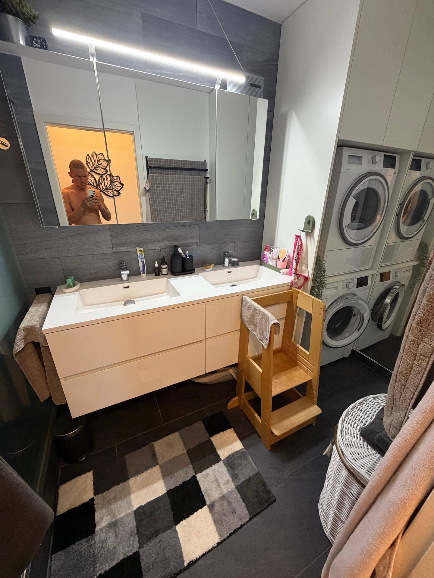Badezimmer mit Doppelwaschbecken, Spiegelschrank und integrierten Waschmaschinen und Trocknern.