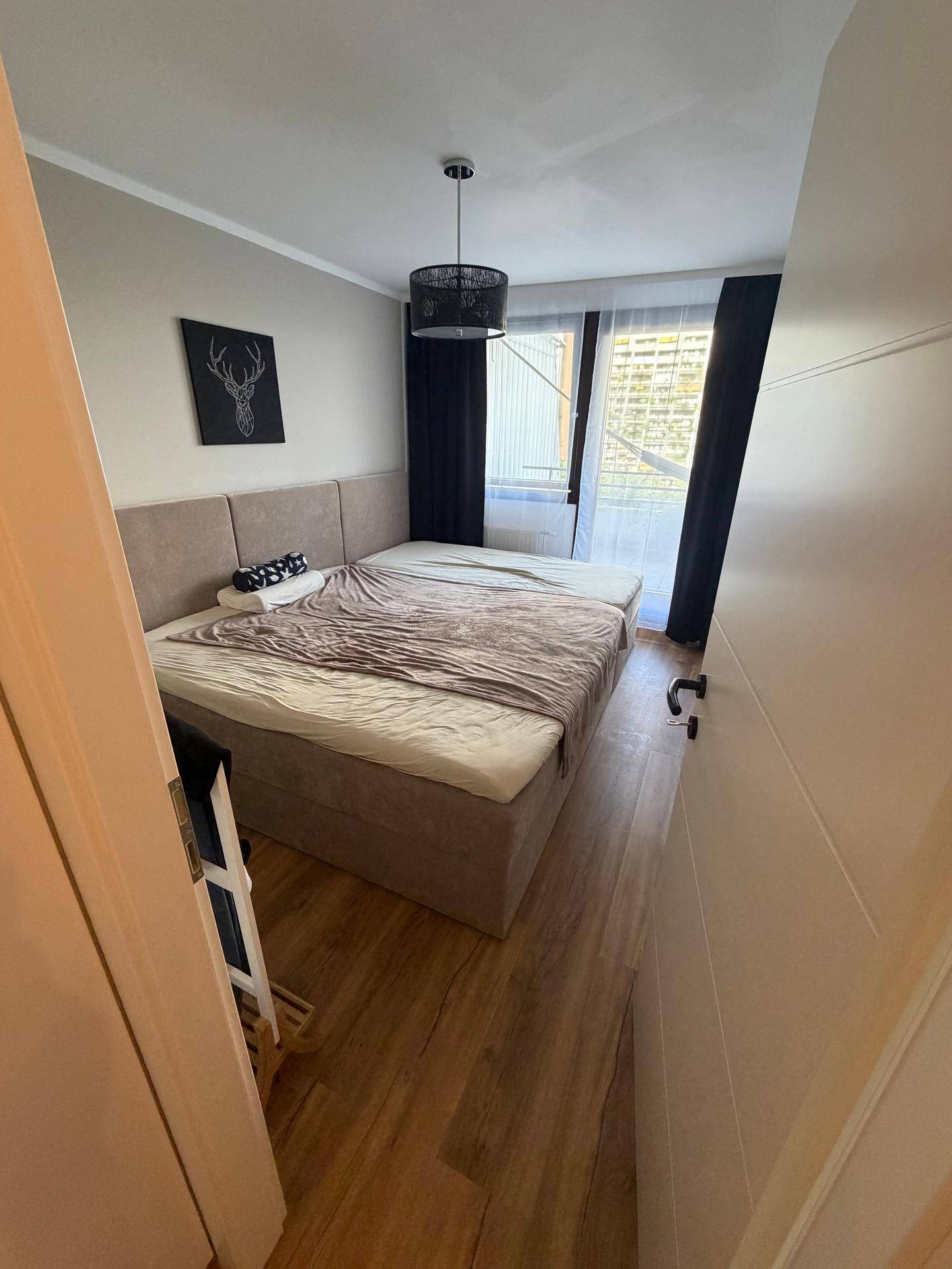 Gemütliches Schlafzimmer mit großem Doppelbett, Holzboden und dunklen Vorhängen.