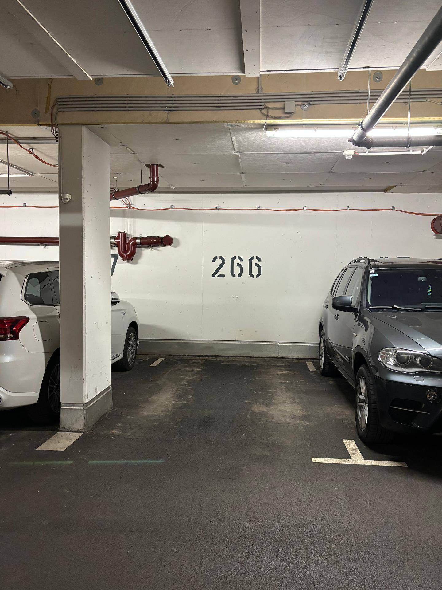 Tiefgaragenstellplatz mit der Nummer 266, umgeben von Betonwänden und Rohren.
