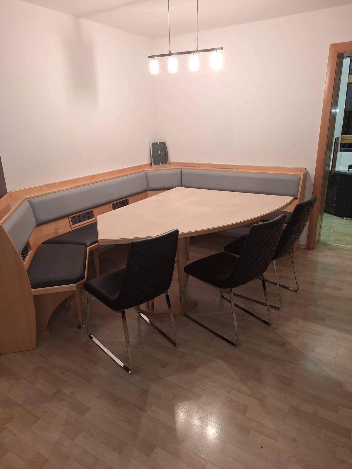Essbereich mit einer gemütlichen Eckbank aus Holz und einem passenden Esstisch auf Laminatboden.