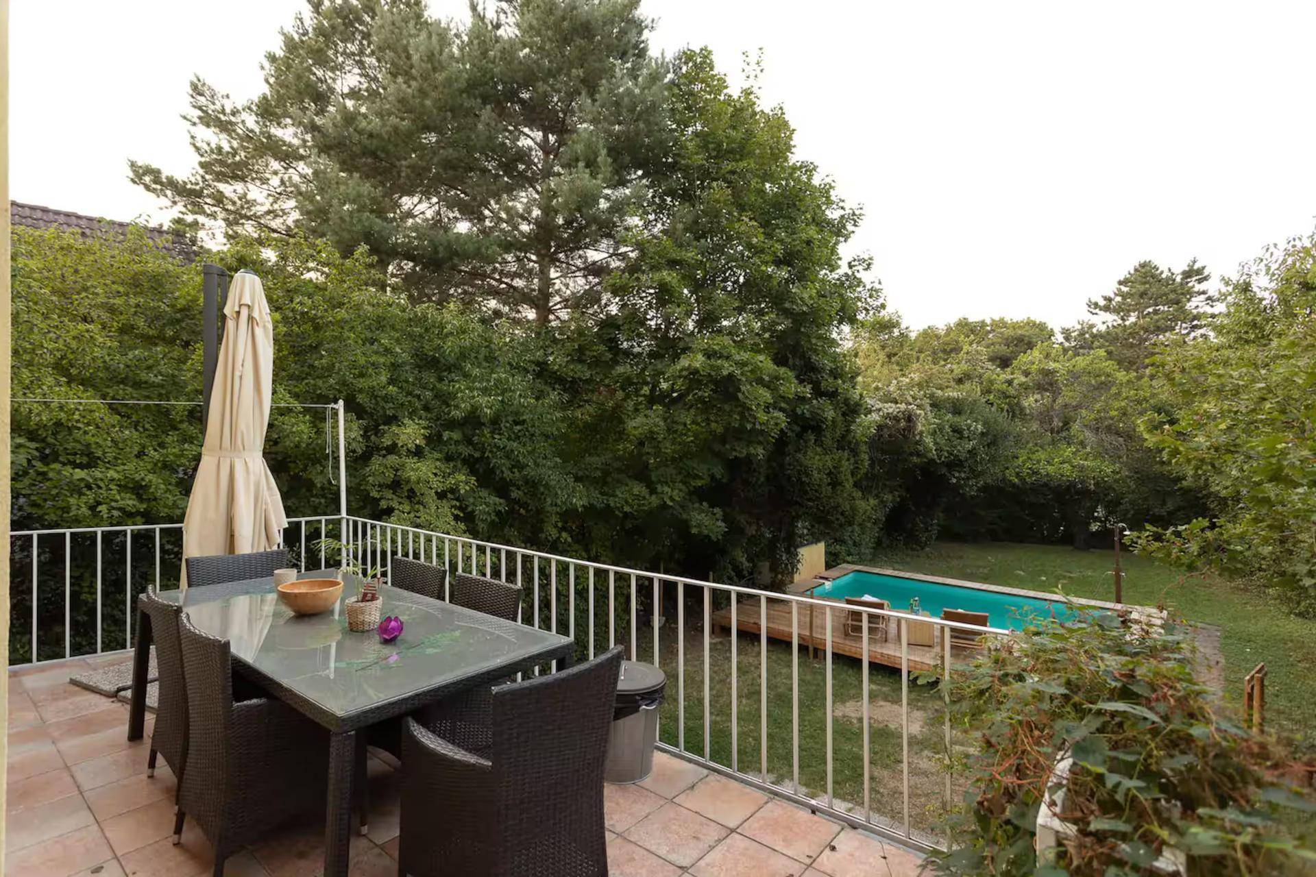 Terrasse mit Esstisch und Blick auf den Garten und den Swimmingpool.