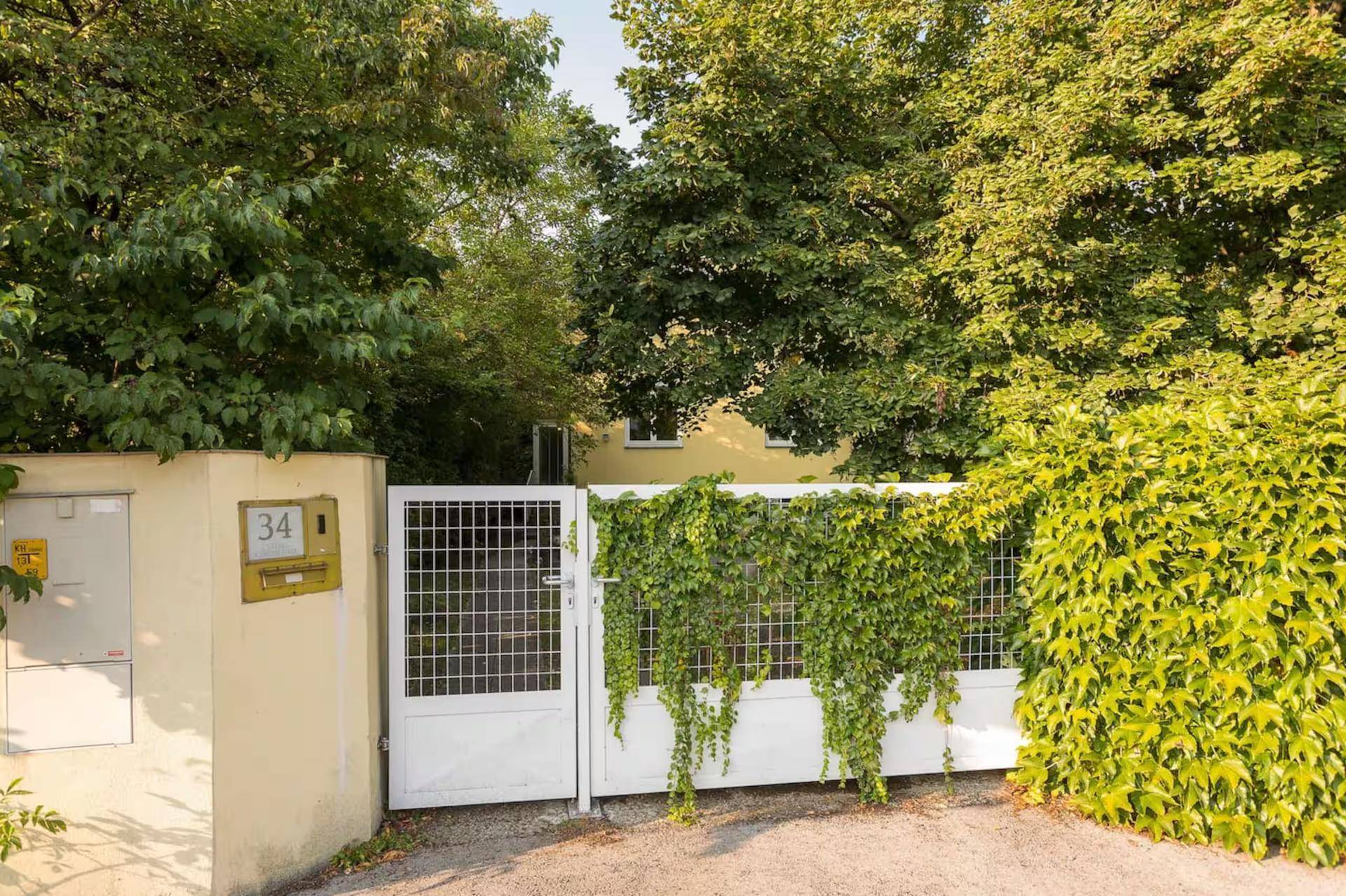 Eingangstor zum Grundstück mit Hausnummer 34, umgeben von üppigem Grün.