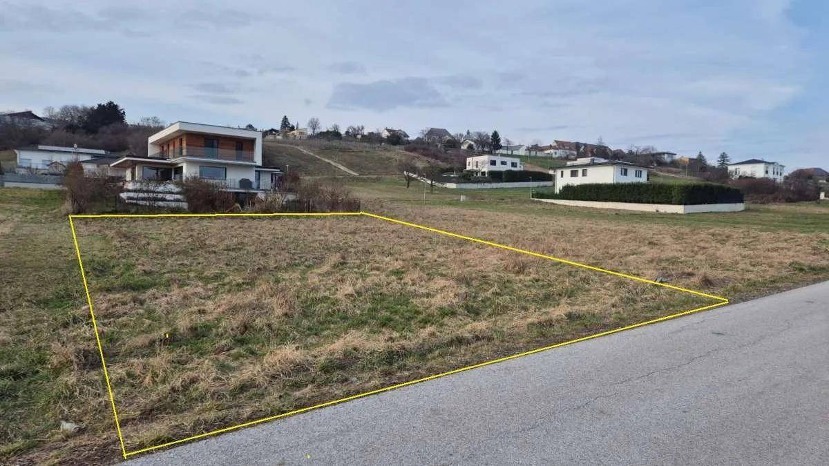 Unbebautes Grundstück mit gelber Markierung und Blick auf umliegende Häuser.