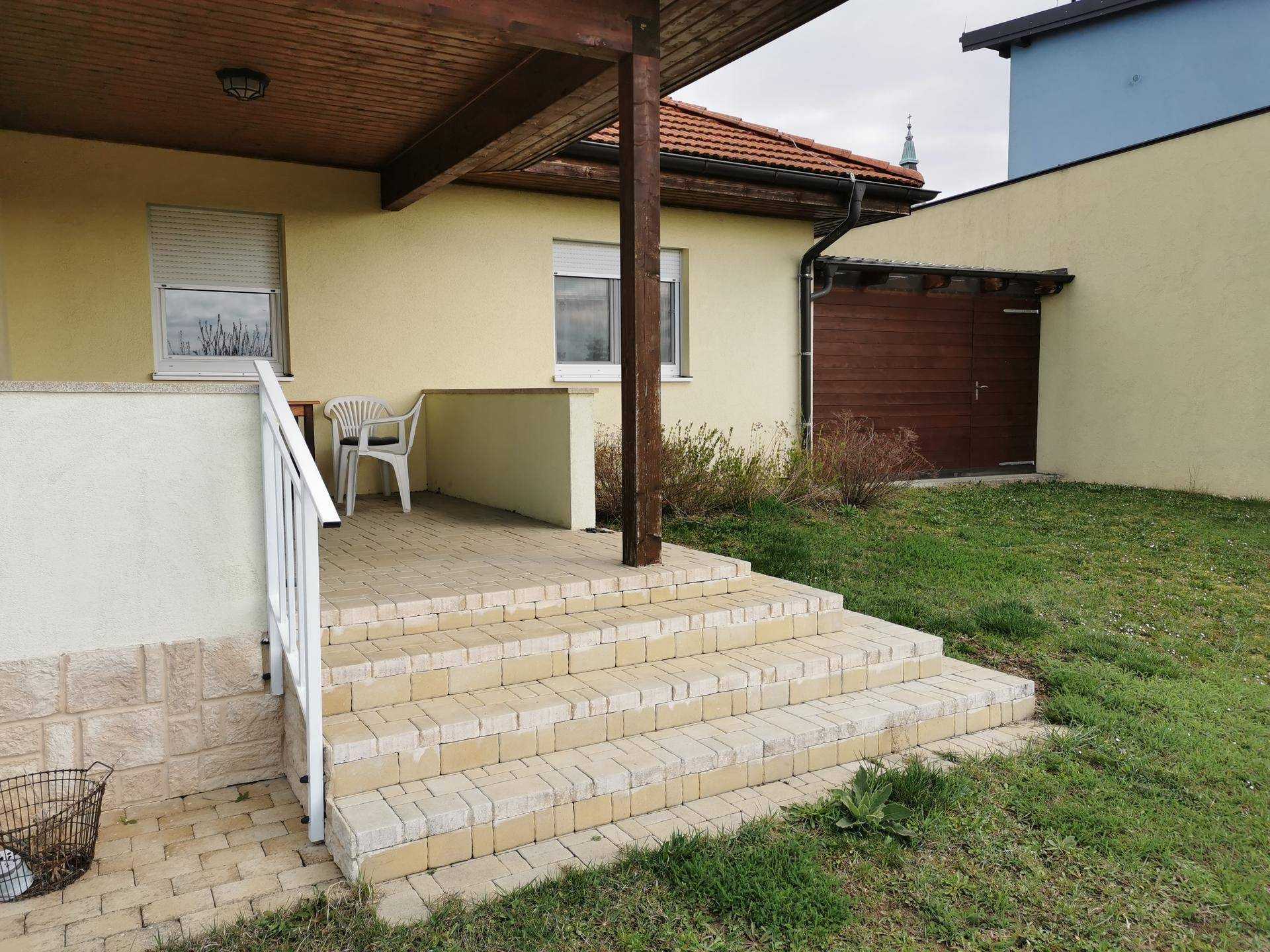 Blick auf die überdachte Terrasse und den angrenzenden Gartenbereich mit Rasenfläche.