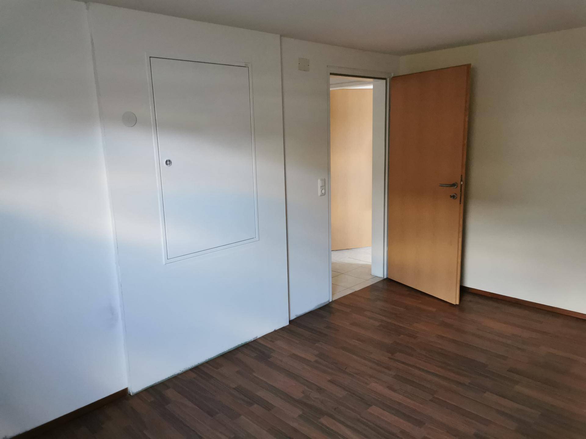 Raum im Untergeschoss mit Laminatboden und Zugang zu einem weiteren Bereich.