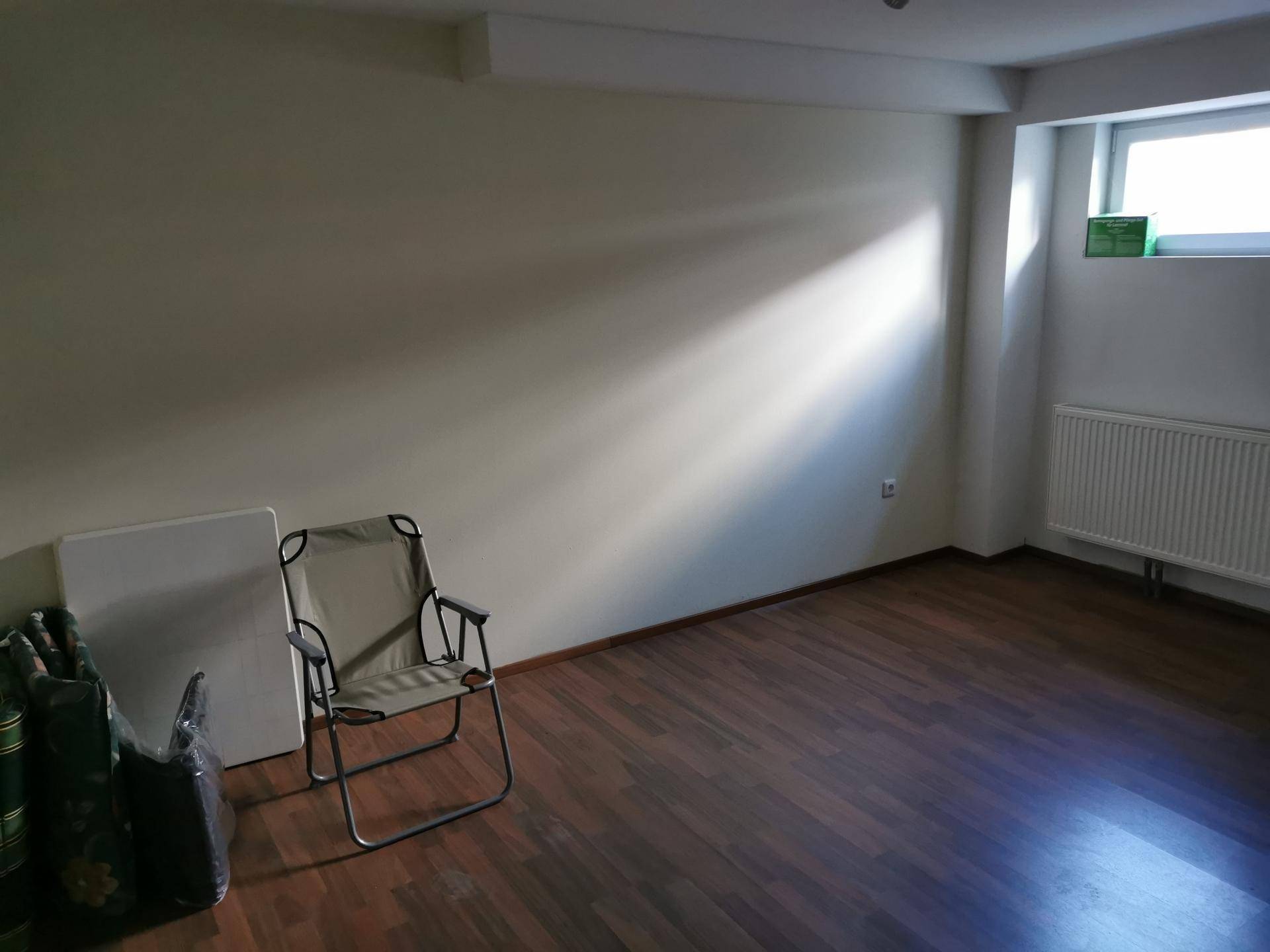 Raum im Untergeschoss mit Laminatboden und Fenster, das Tageslicht hereinlässt.