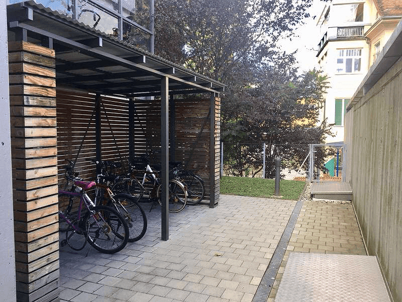 Überdachter Fahrradabstellplatz mit Holzverkleidung im Außenbereich der Wohnanlage.
