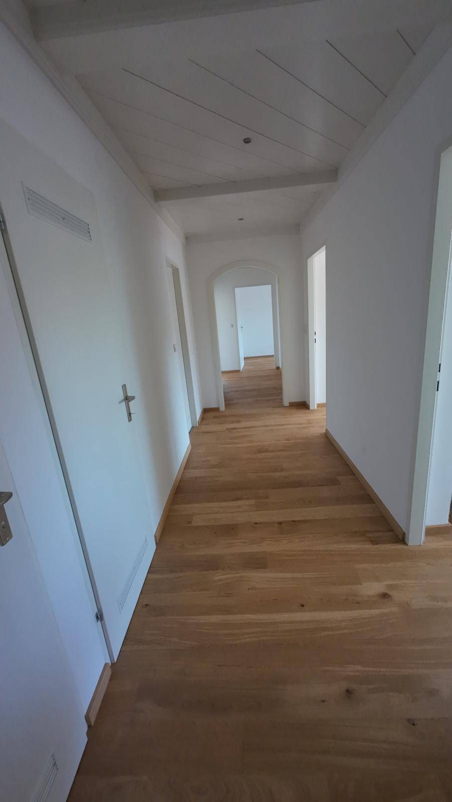 Heller Flur mit Holzparkettboden und einer charakteristischen Holzdeckenverkleidung.