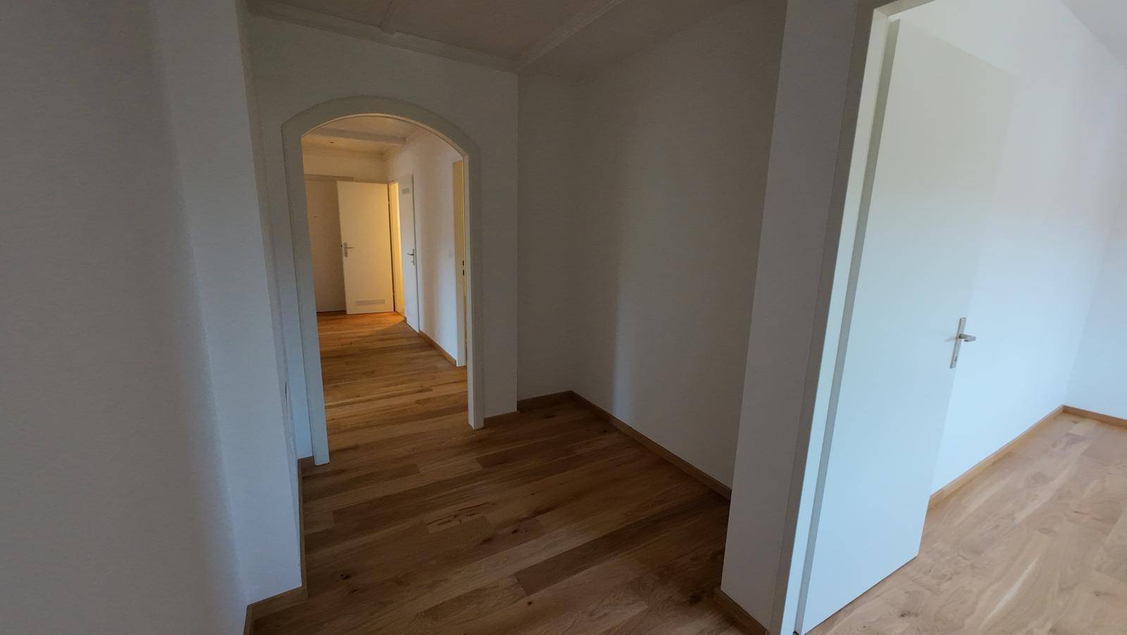 Gangbereich mit Holzboden und einem eleganten Rundbogen, der zu weiteren Räumen führt.