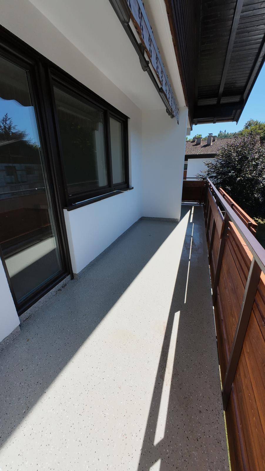 Sonniger Balkon mit Holzbalkonbrüstung und Blick auf die umliegende Bebauung.