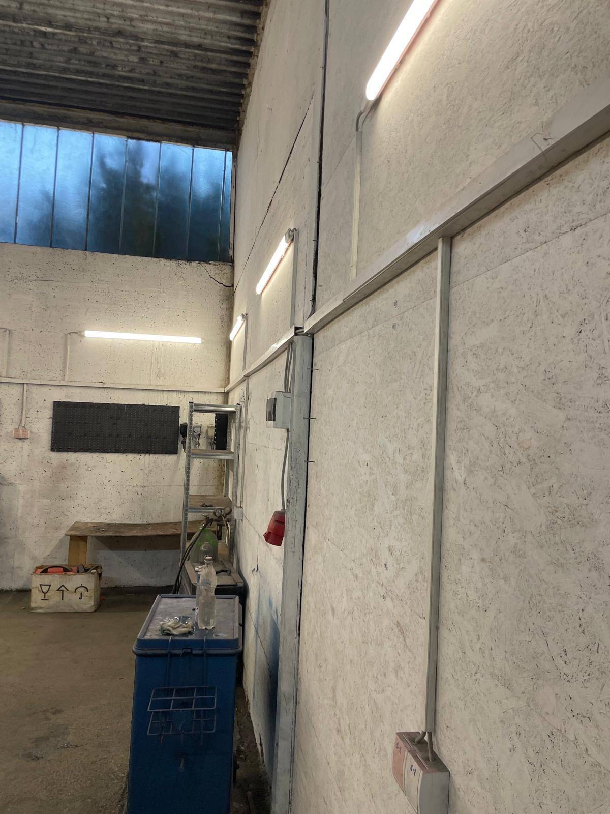 Detailansicht einer Betonwand im Werkstattbereich mit Beleuchtung und elektrischen Installationen.