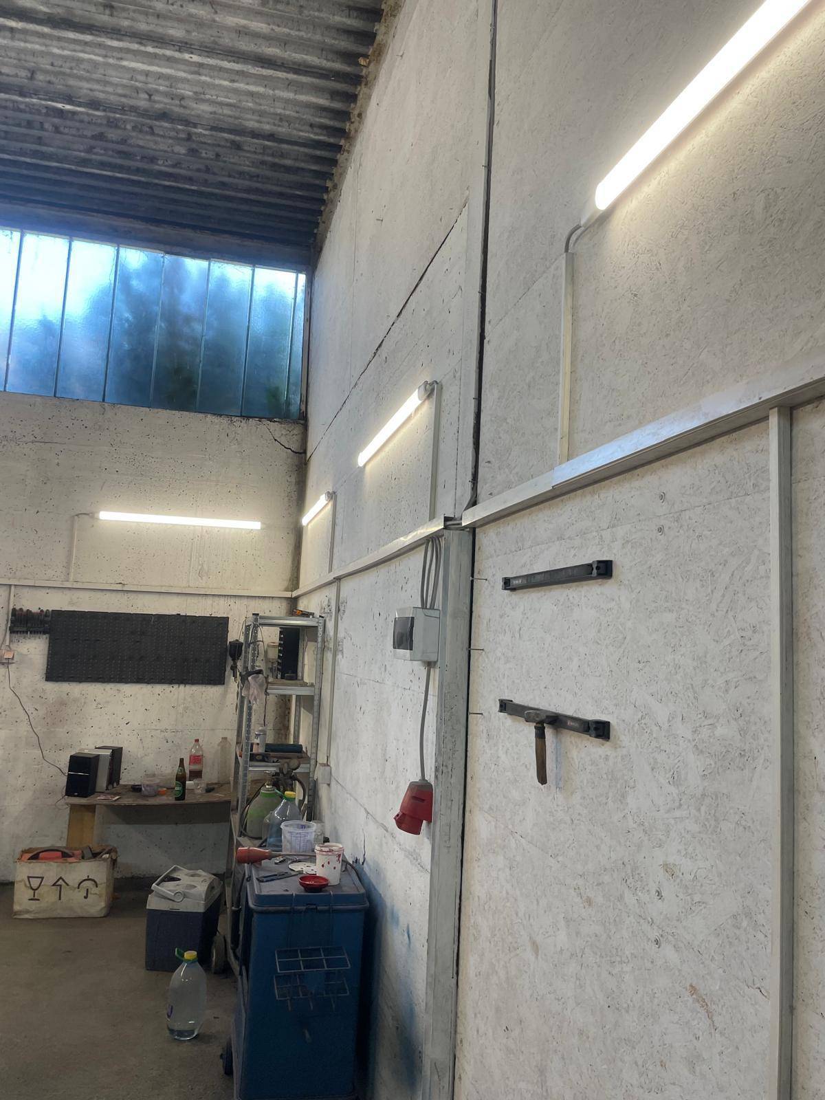 Wandbereich im Werkstattraum mit OSB-Platten, Beleuchtung und sichtbaren elektrischen Anschlüssen.