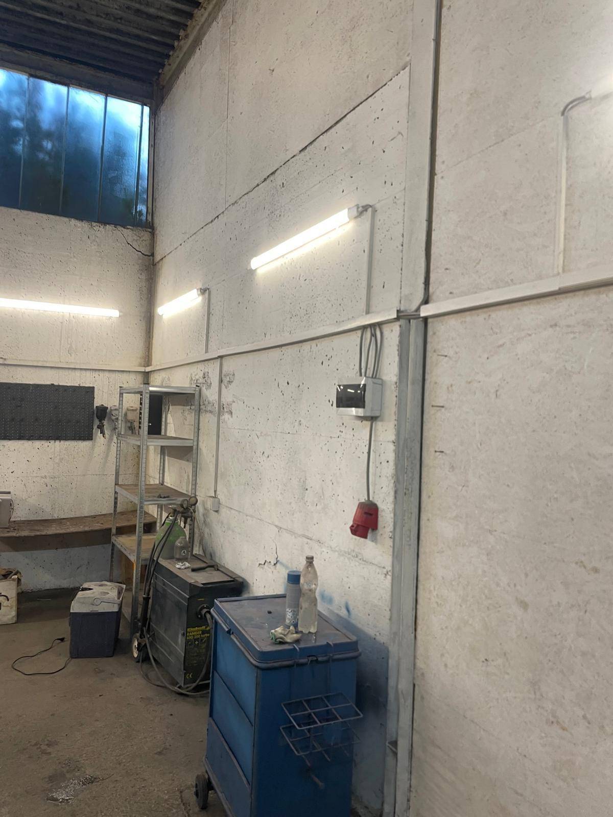 Detailansicht einer Betonwand im Werkstattbereich mit Beleuchtung und elektrischen Installationen.