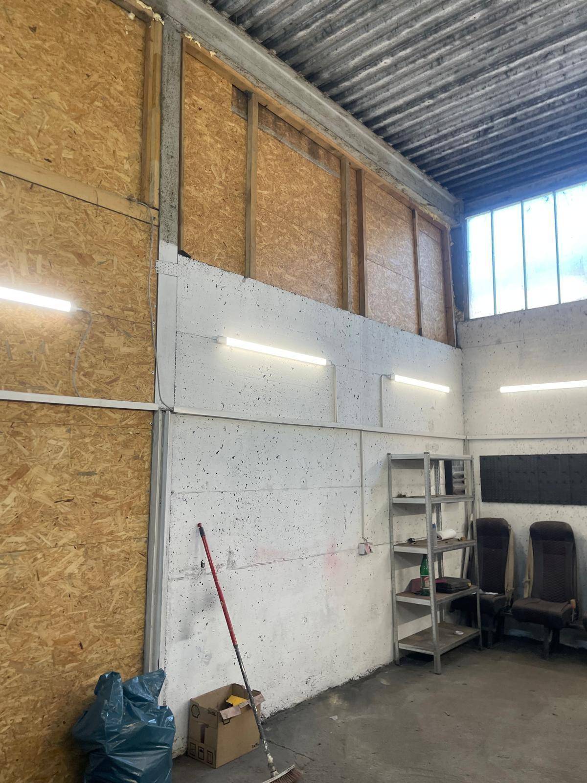 Blick auf die Wände eines Werkstattraums mit OSB-Platten und rauer Betonstruktur.