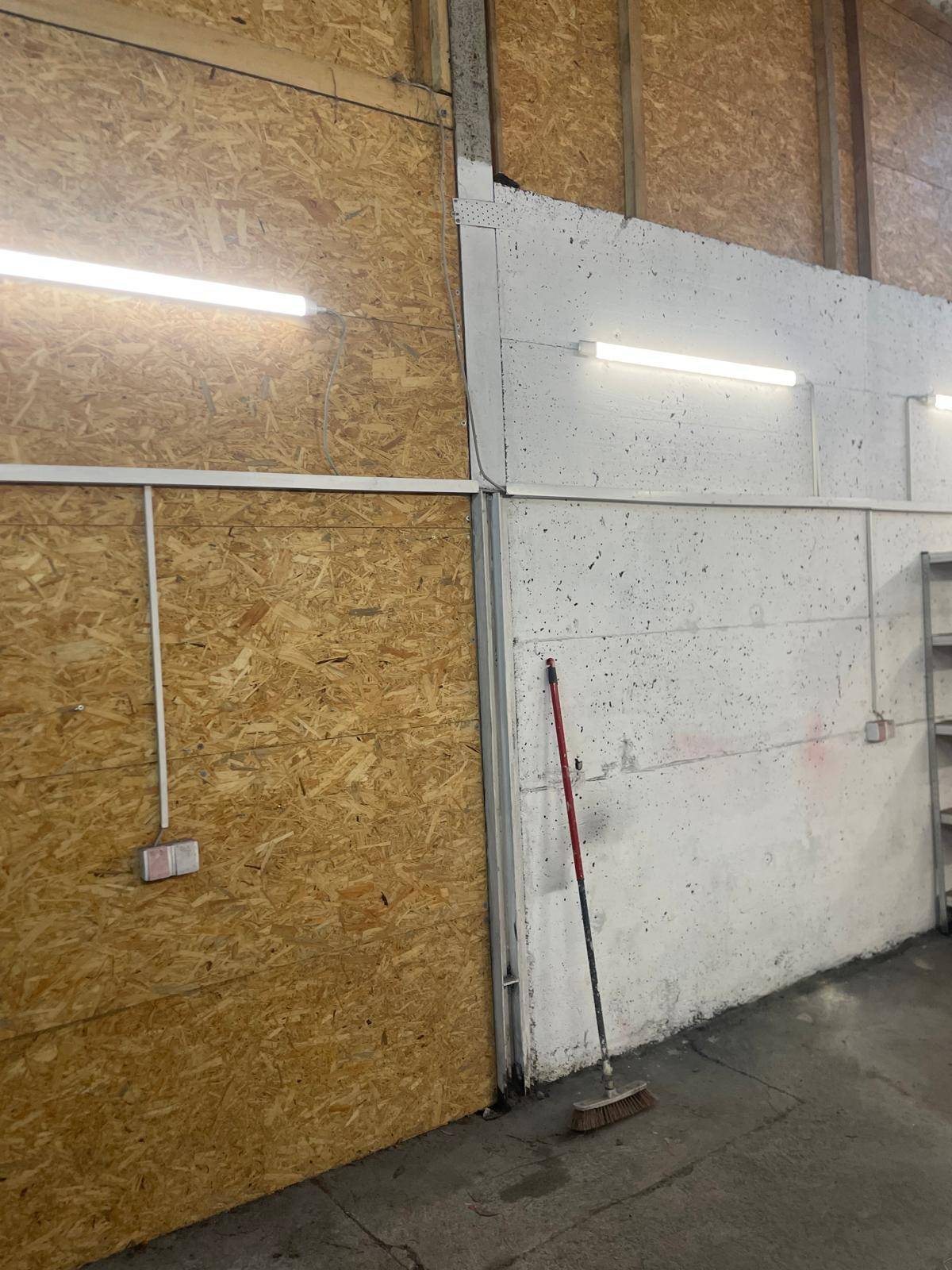 Wände eines Werkstattraums mit OSB-Platten und rauen Betonoberflächen.