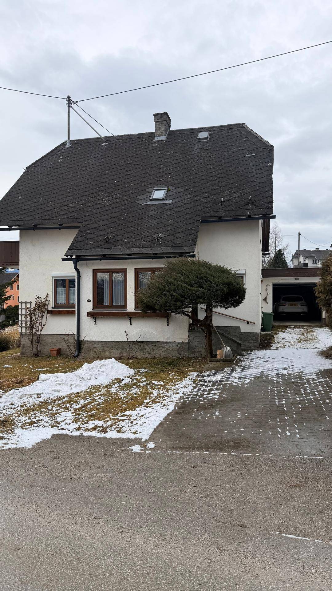 Ansicht des Hauses von der Seite mit Einfahrt und integrierter Garage im Winter.