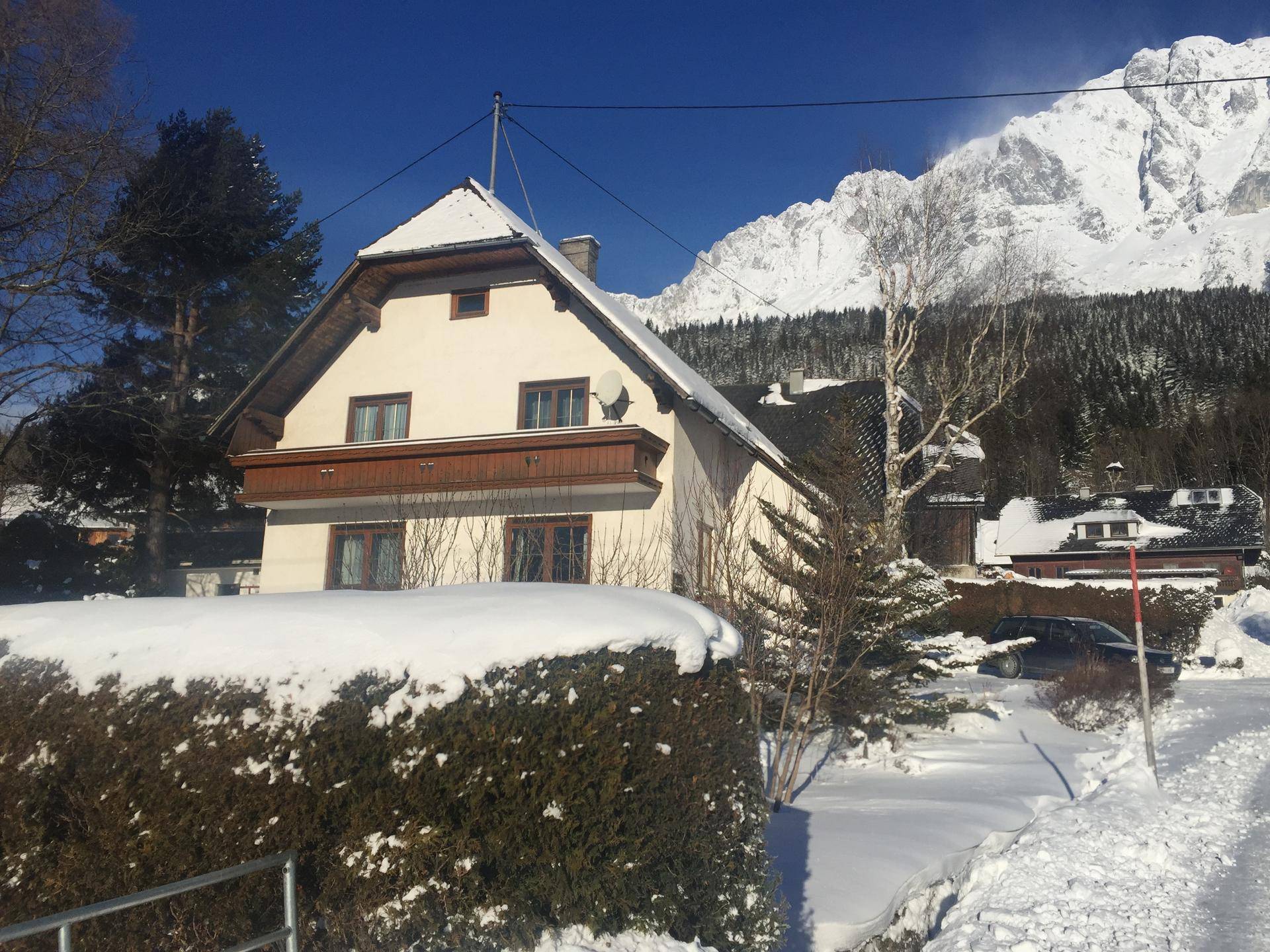 Haus im Winter mit Schnee bedeckt, klarem Himmel und majestätischem Bergblick.