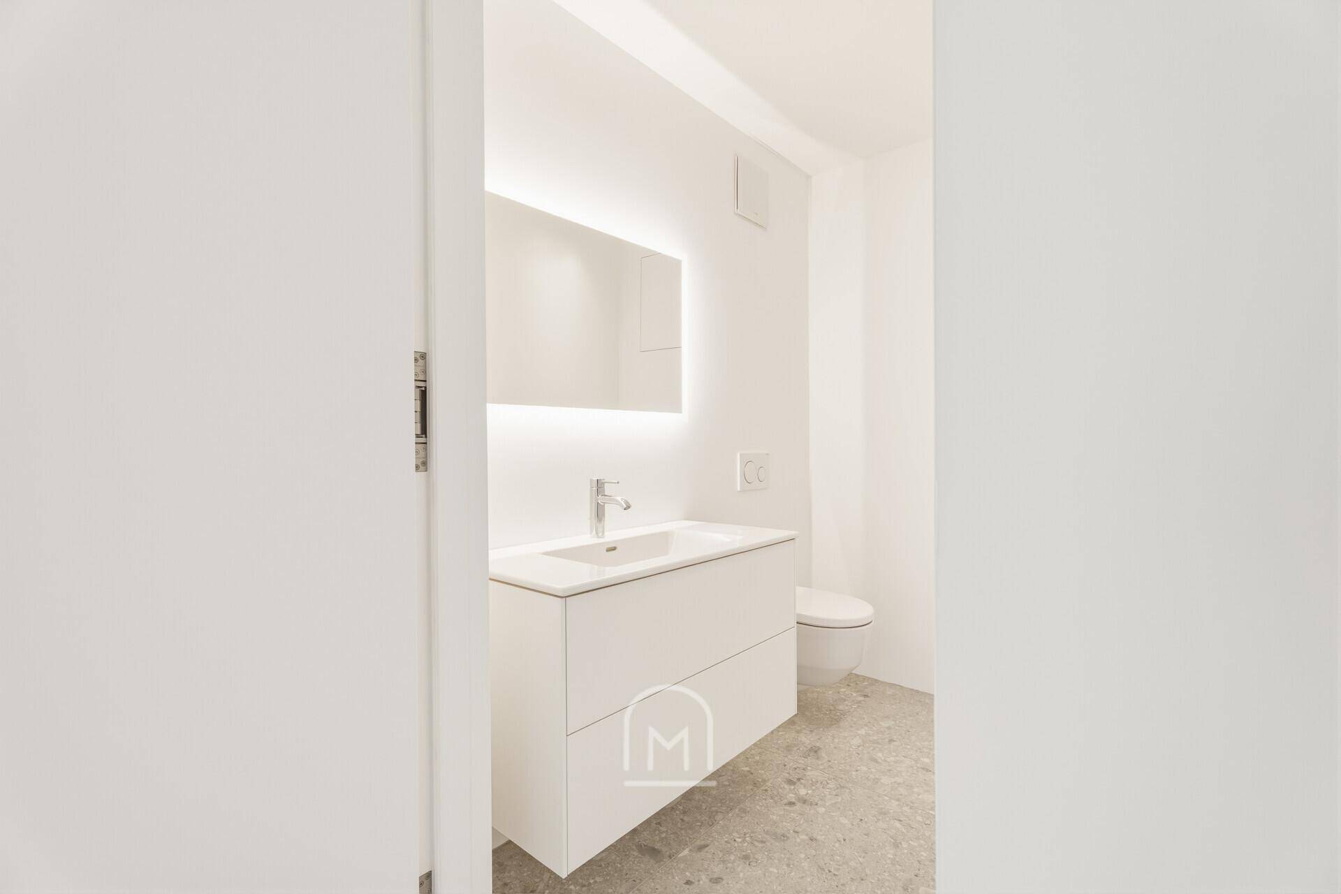 Helles, modernes Badezimmer mit elegantem Waschtisch, beleuchtetem Spiegel und wandhängendem WC.