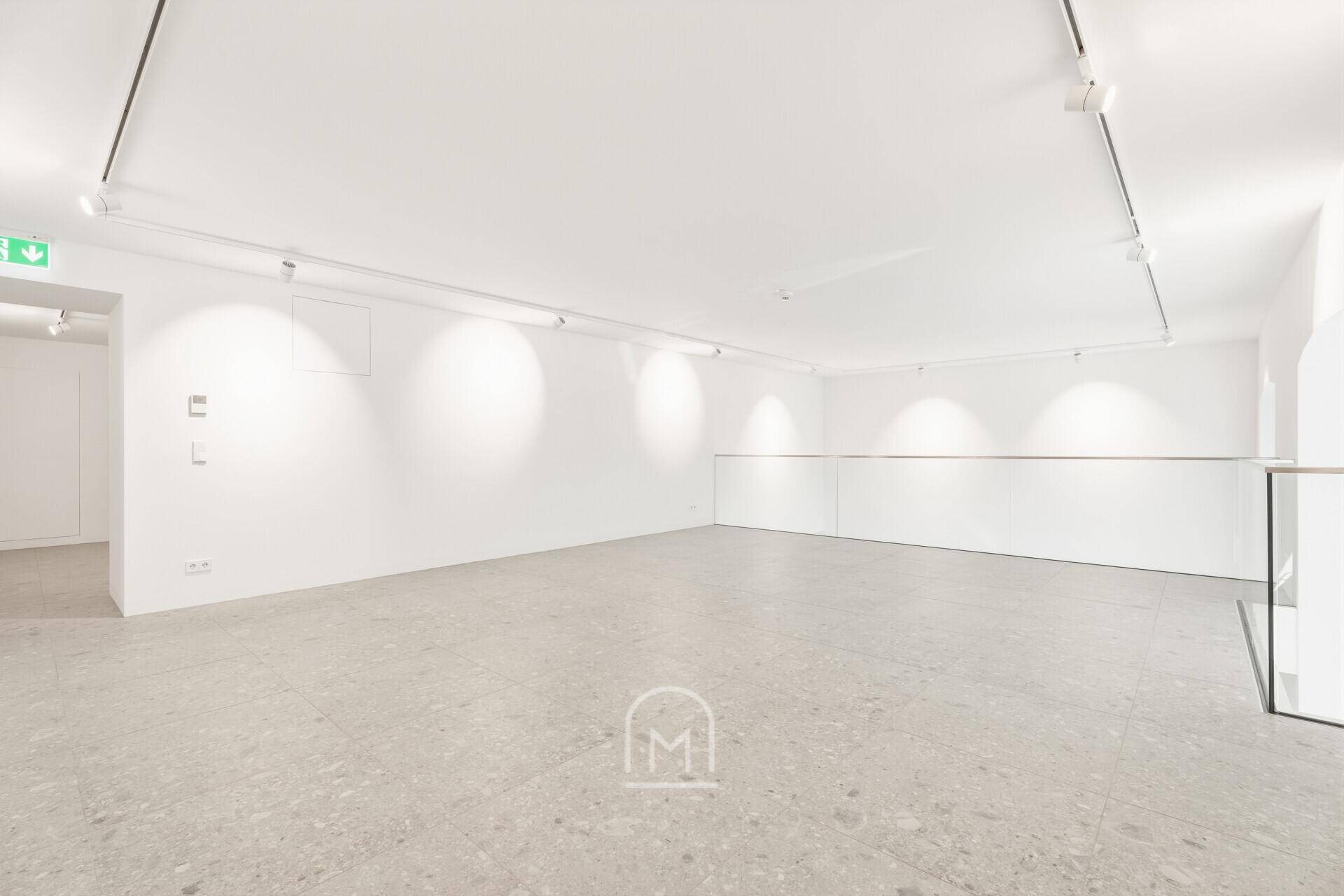 Helle Galerieebene mit moderner Schienenbeleuchtung und Blick auf den unteren Bereich.